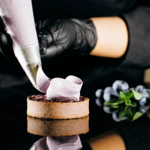Chef using an icing piping bag to decorate a dessert, symbolizing the extrusion process of aluminum.