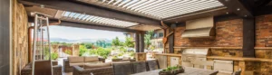 Luxurious outdoor kitchen under a louvered pergola with scenic mountain view.