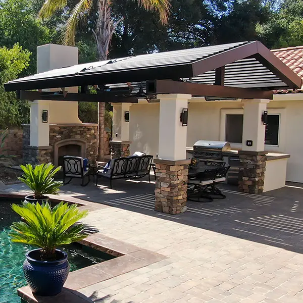 Pergola providing shade over a poolside outdoor kitchen and seating area.