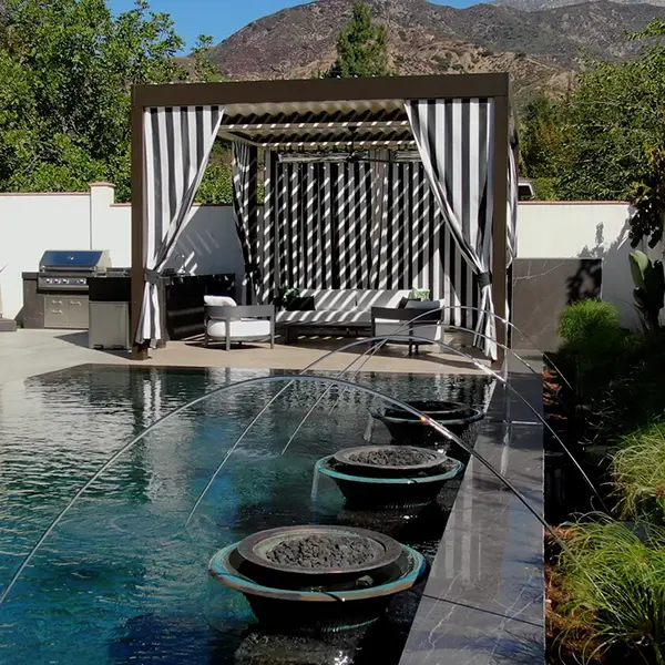 Pergola with privacy curtains installed beside a pool, providing shade and seclusion.